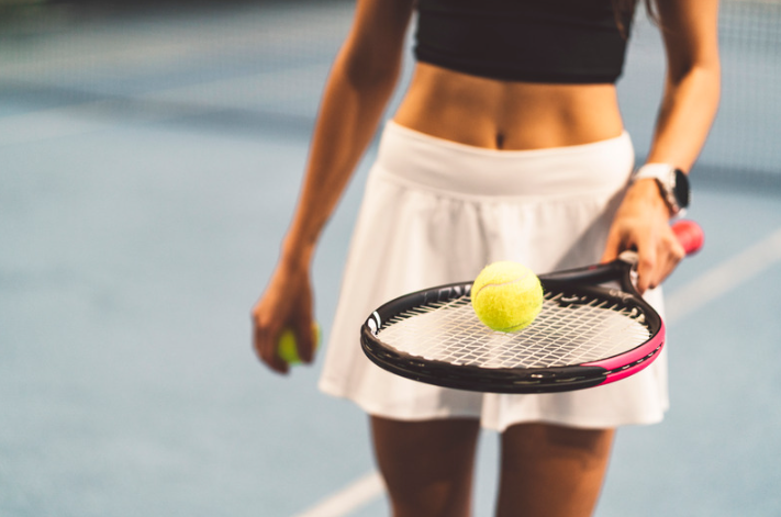 woman balancing a tennis ball on a racket